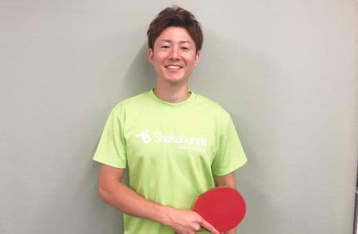A Shakehands Club coach holding a racket in the table tennis hall
